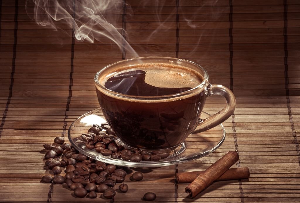 Philco Coffee Express 1 1 Xícara com café puro fumaçando sobre a mesa e alguns grãos de café espalhados